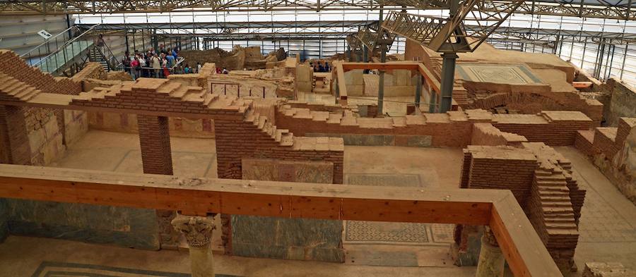 Interior de las Casas de la Ladera de Éfeso bajo su cubierta moderna, con muros de ladrillo, suelos de mosaico y pasarelas de madera